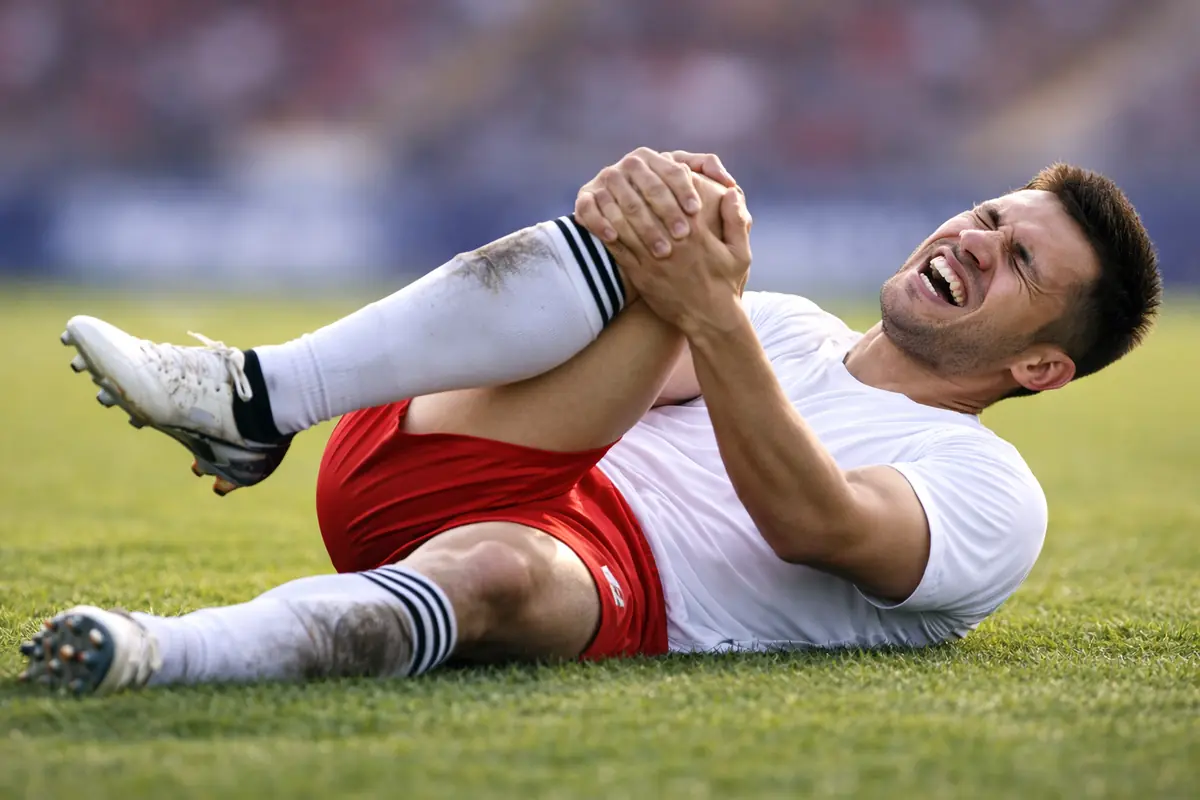 Giocatore infortunato si tiene il ginocchio